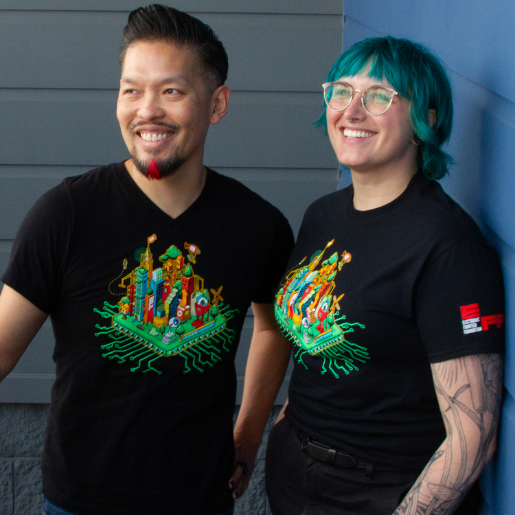 Two people wearing black t-shirt with a green EFF 35th Anniversary digital cityscape on the front.